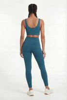 Person wearing a teal sports bra and leggings set on a white background