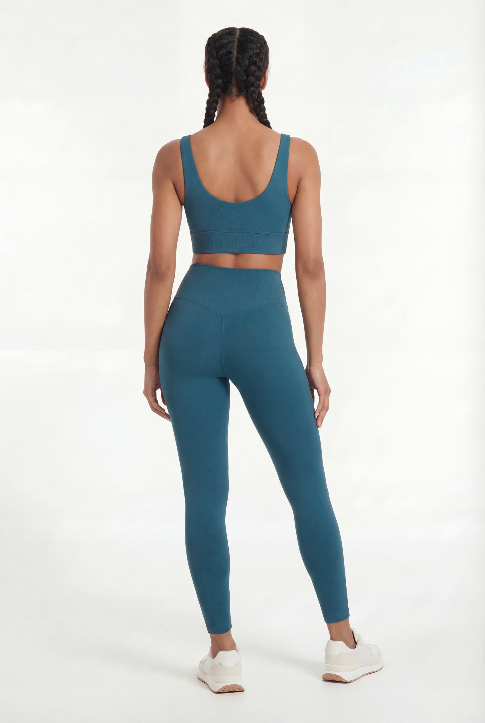 Person wearing a teal sports bra and leggings set on a white background
