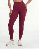 Woman wearing a burgundy sports bra and leggings set on a white background