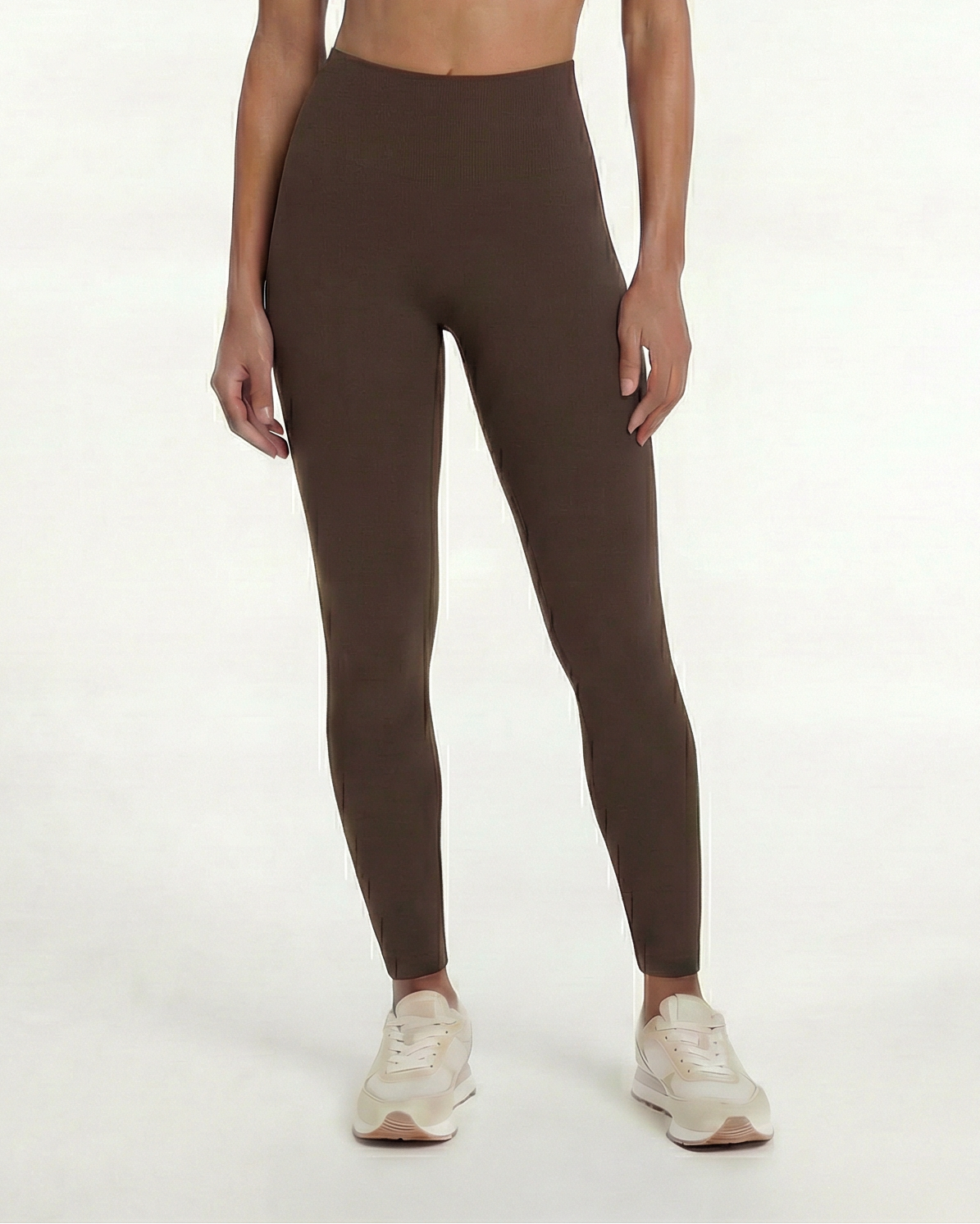 Woman wearing a brown sports bra and leggings set on a white background