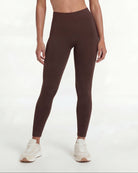 Woman wearing a brown sports bra and leggings set on a white background